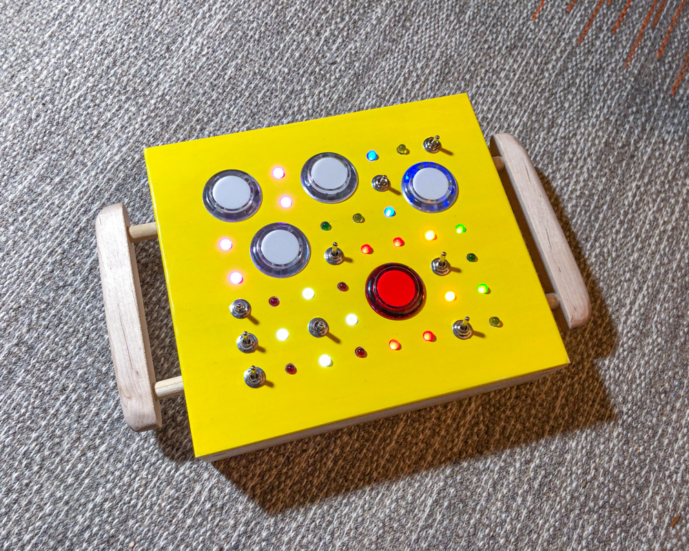 Yellow toy with switches and buttons on a rug